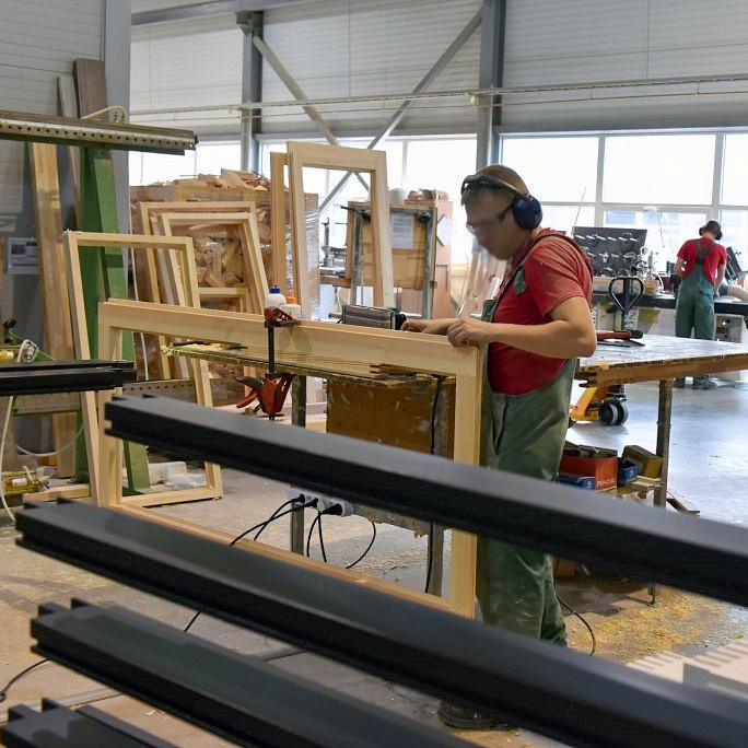 darbinieks izgatavo koka logus ražotnē Latvijā